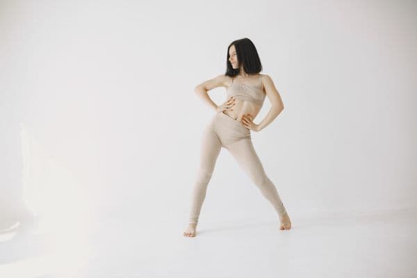 A dancer in a wide standing pose, with her hands on her hips.